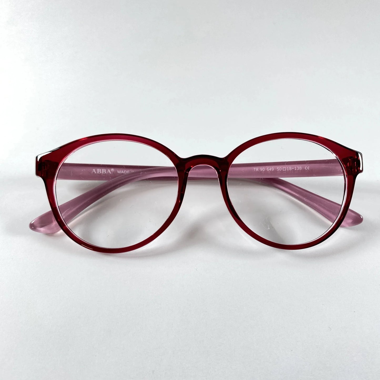 Round burgundy eyeglasses with clear lenses on a white background