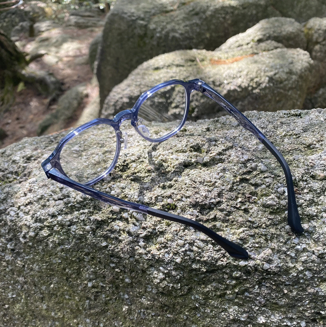 VionGlasses Korean-made panto shape glasses in navy placed on Halla Mountain rocks.