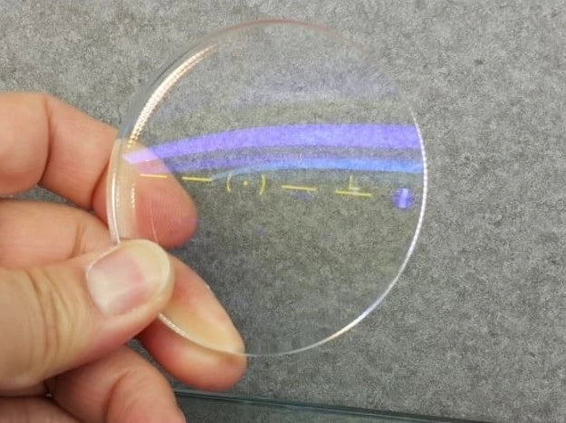Close-up of a premium hi-index eyeglass lens with blue-light filtering, UV400 protection, and anti-reflective coating for clear prescription vision.