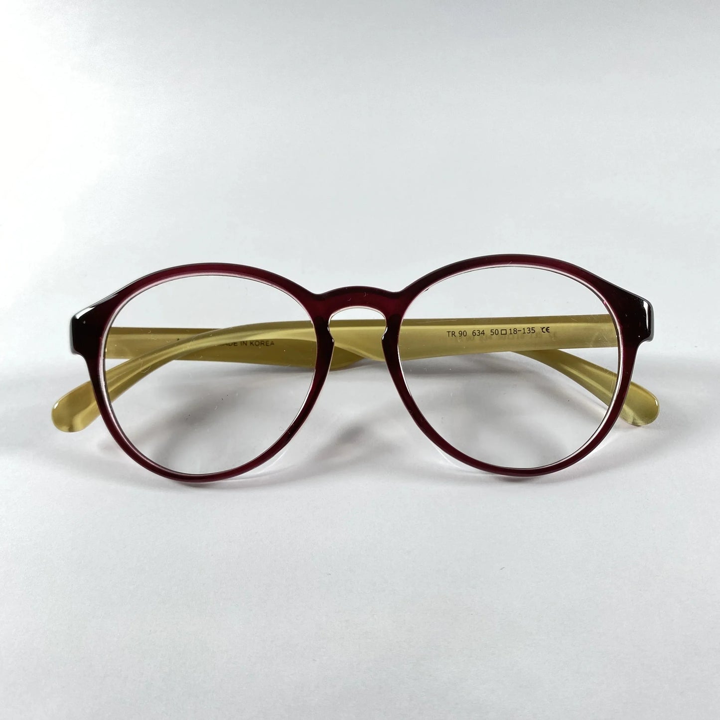 Brown glossy round eyeglasses with yellow arms on a white background