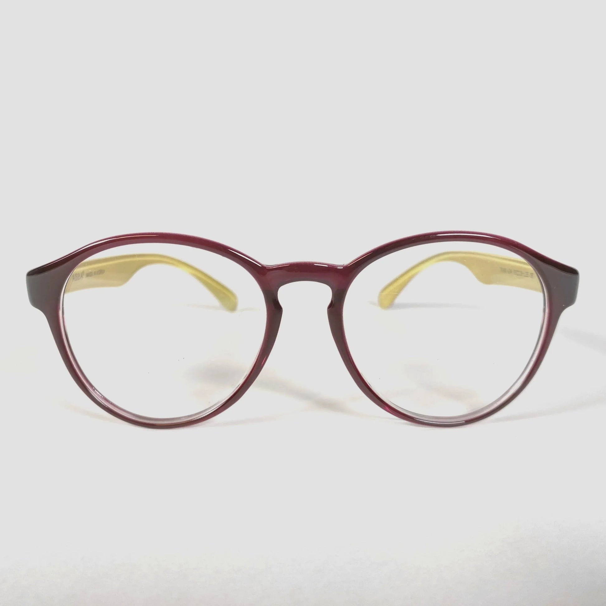 Brown glossy round eyeglasses with yellow temples on white background