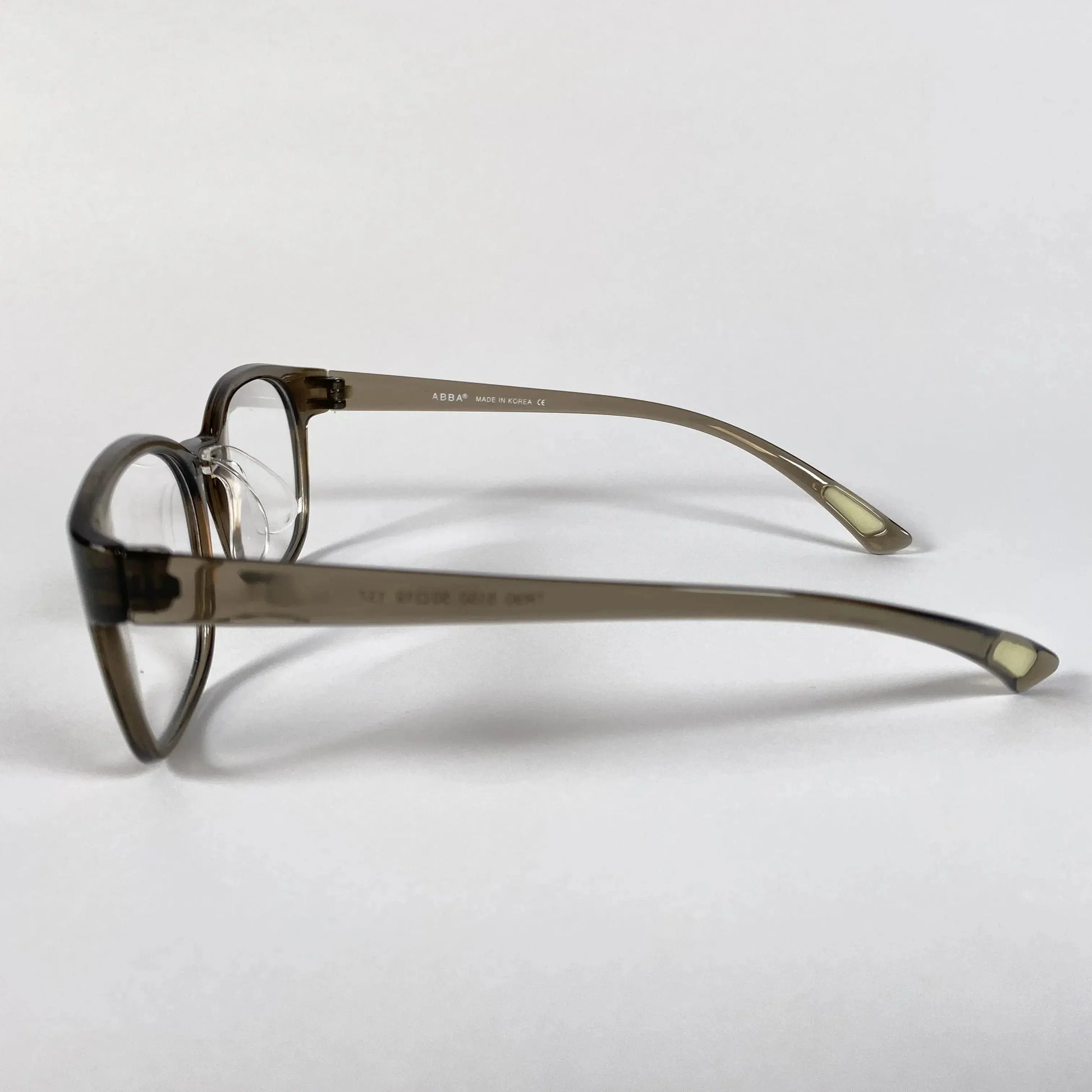 Olive green round eyeglasses with clear nose pads on white background, side view