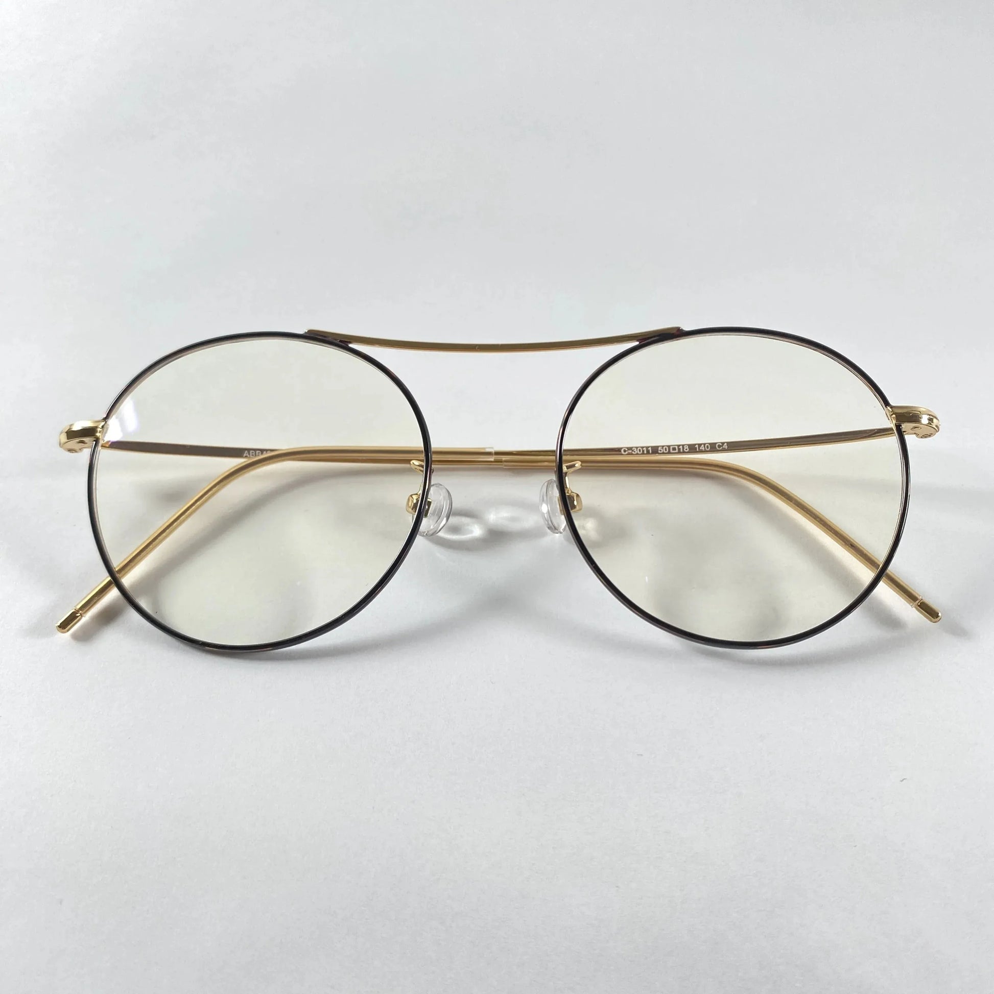 Gold round eyeglasses with metal frames and clear lenses on white background