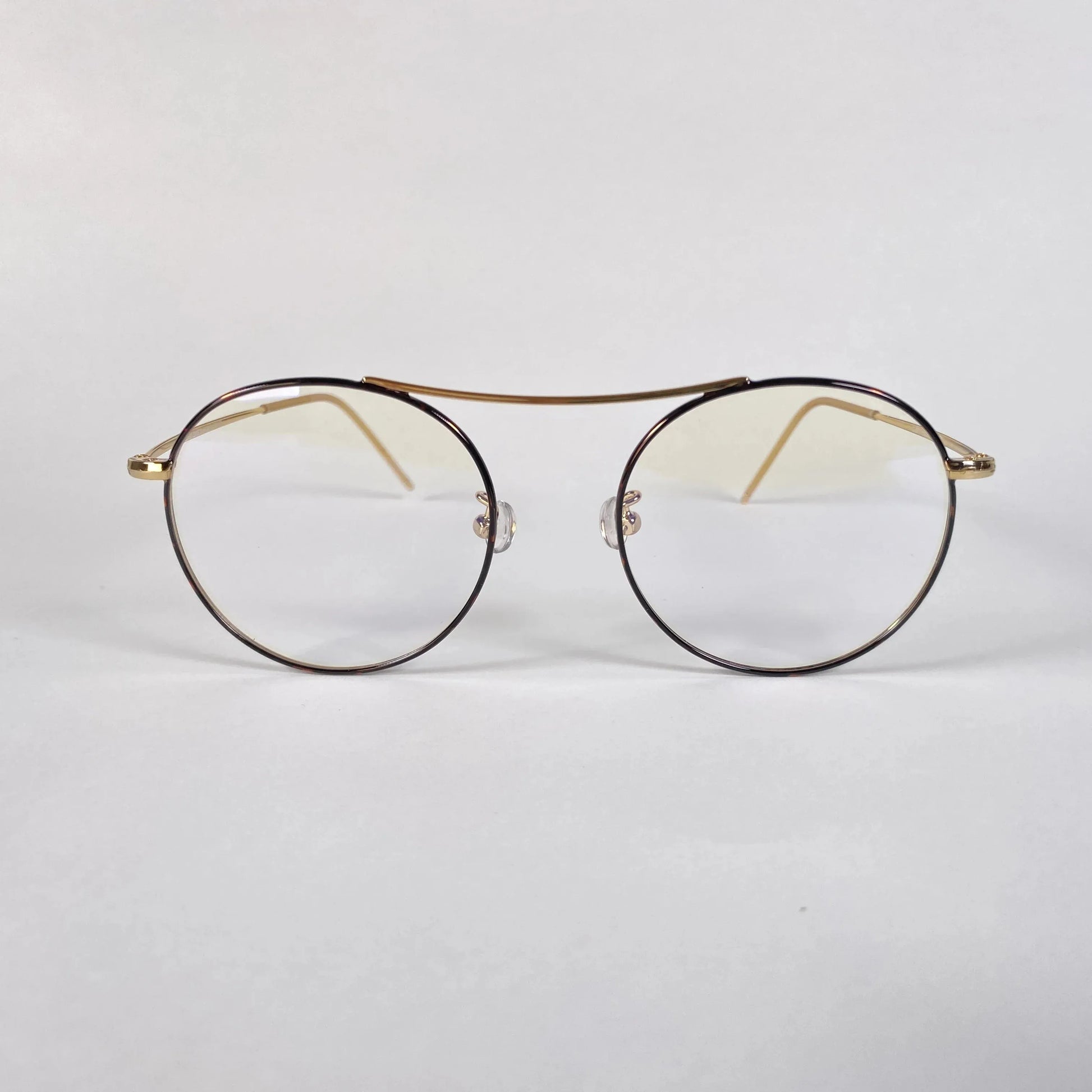 Gold round eyeglasses with clear lenses and thin metal frame on white background
