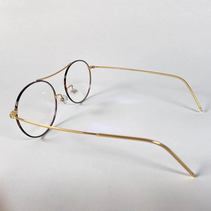 Gold round metal eyeglasses with clear nose pads on white background