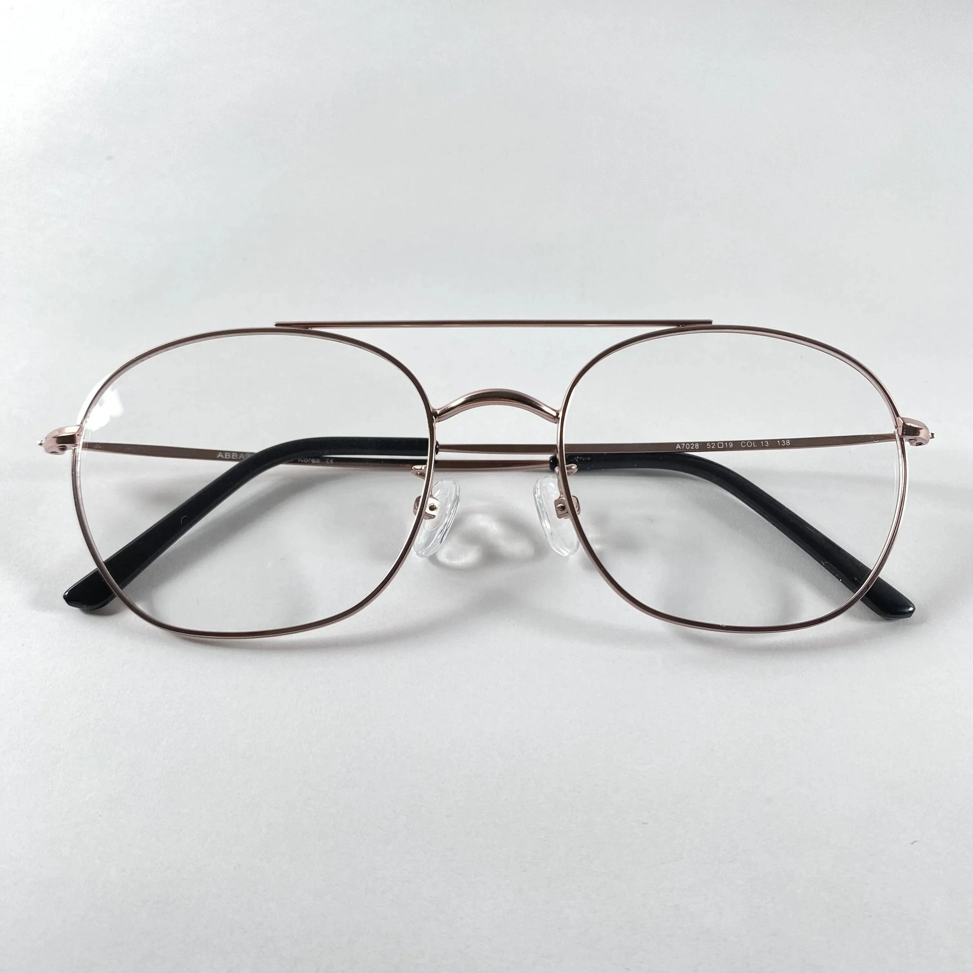 Rose gold pilot eyeglasses with thin metal frame and clear lenses on white background