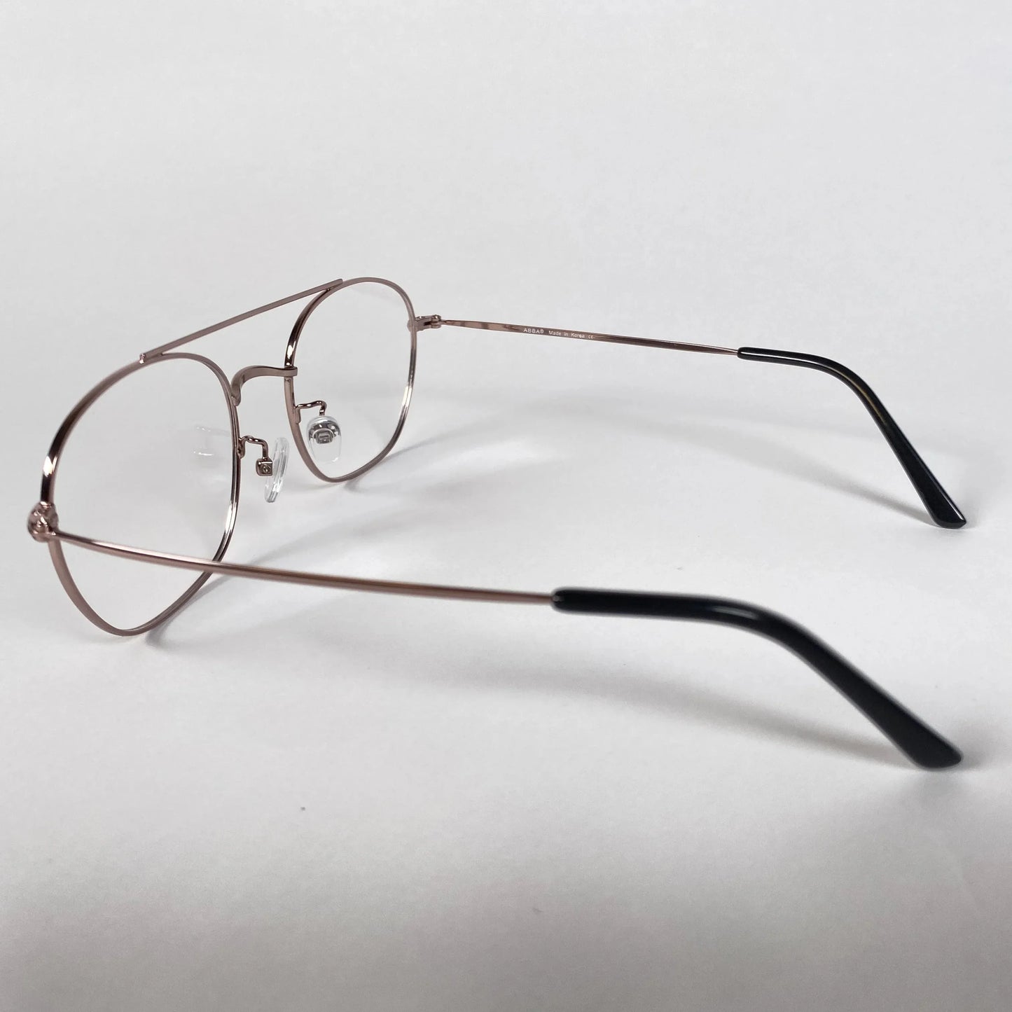 Rose gold round metal pilot eyeglasses with black temple tips on white background