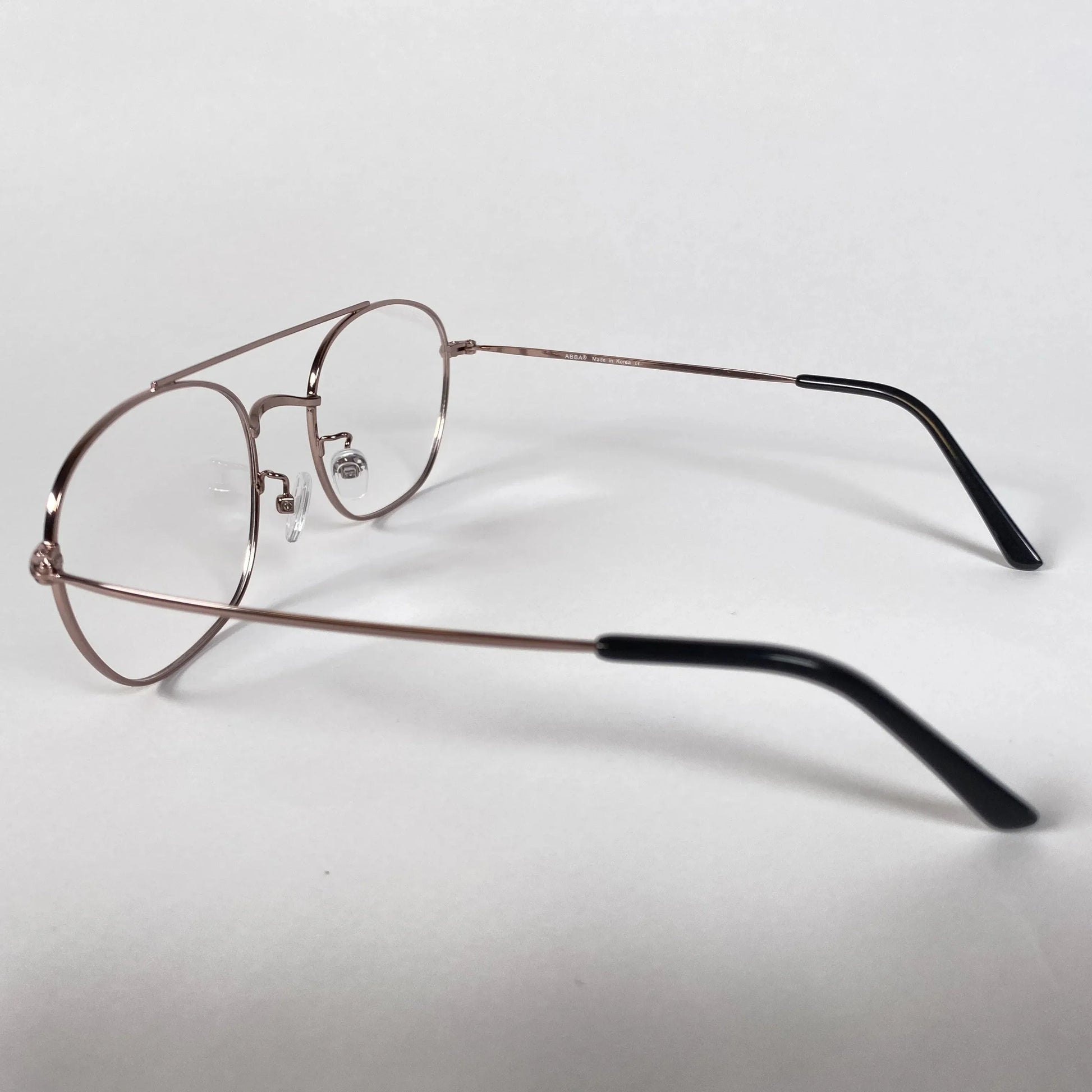 Rose gold round metal pilot eyeglasses with black temple tips on white background