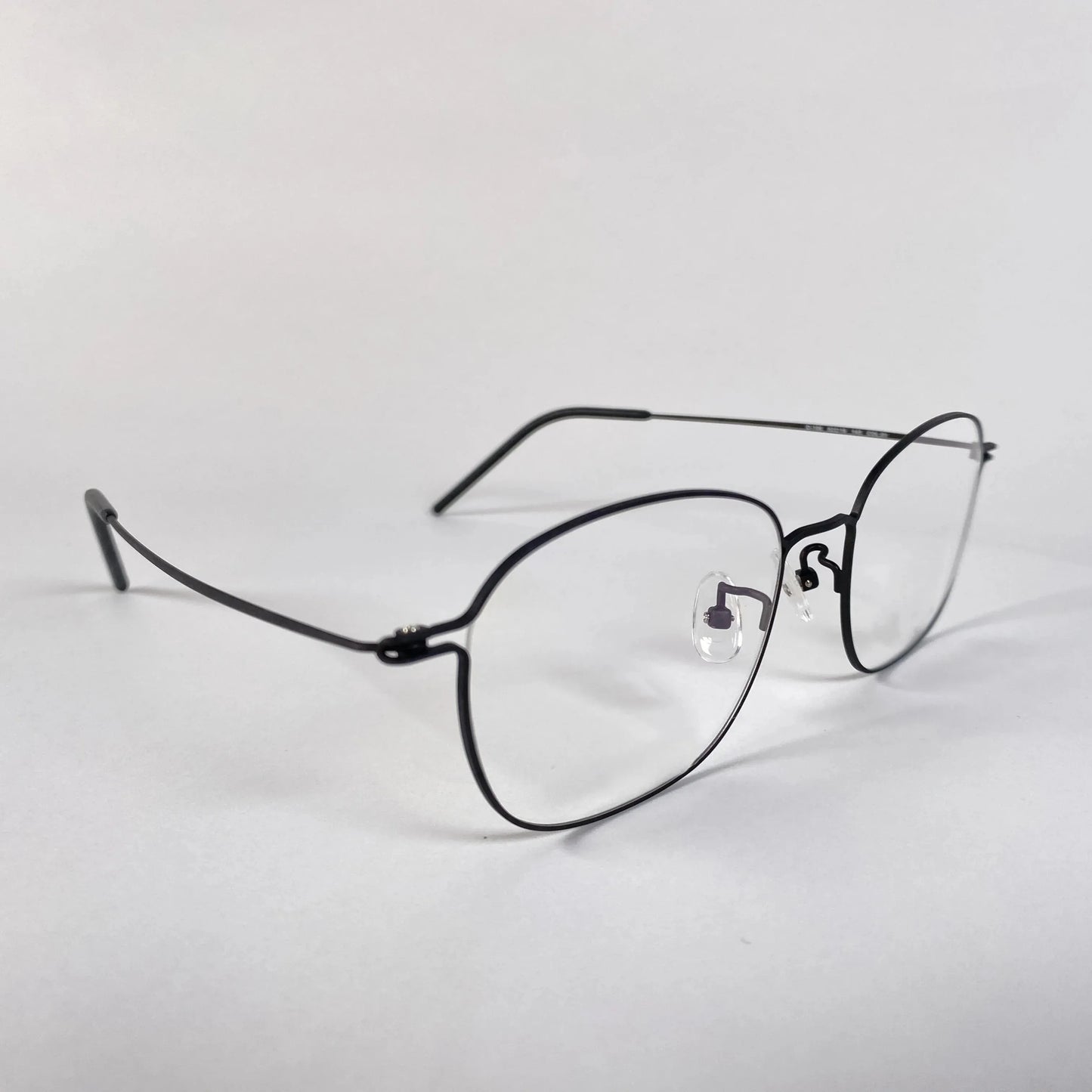 Titanium eyeglasses with thin black frame and clear nose pads on a white background