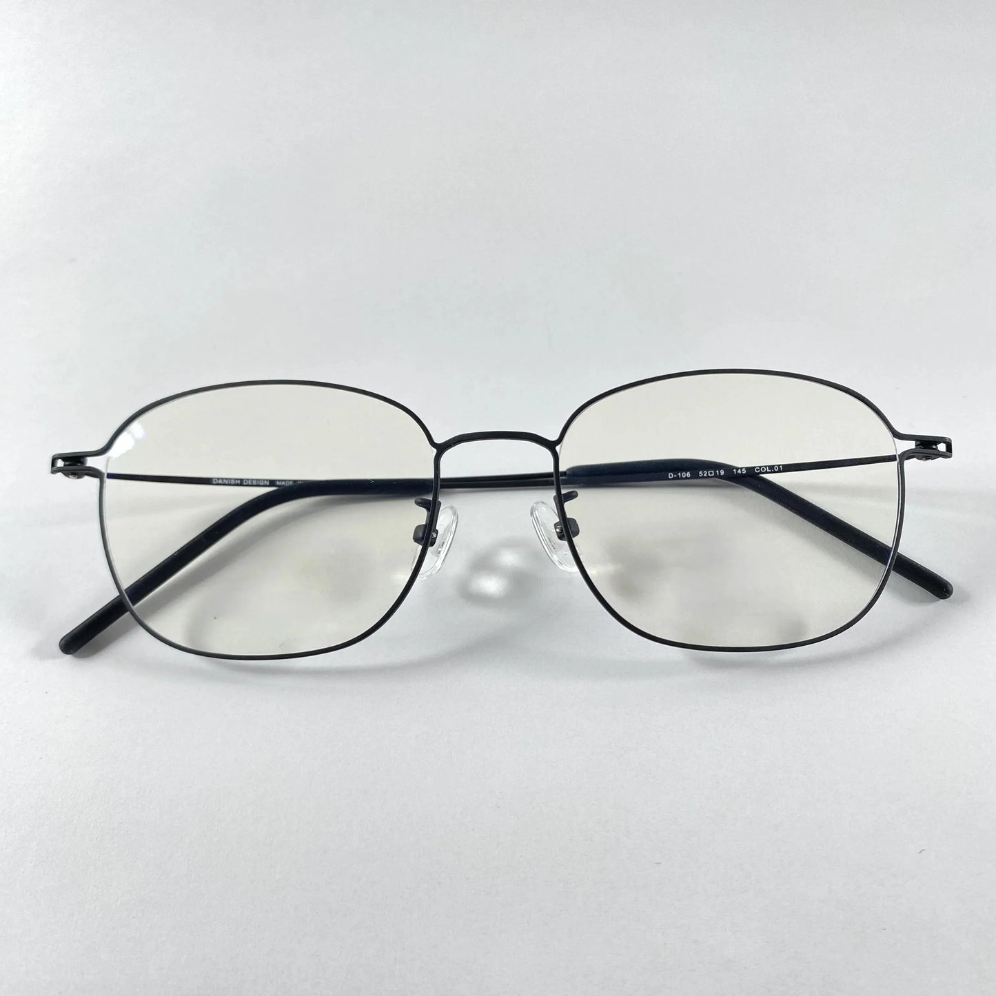 Titanium eyeglasses with thin black frame and clear lenses on white background