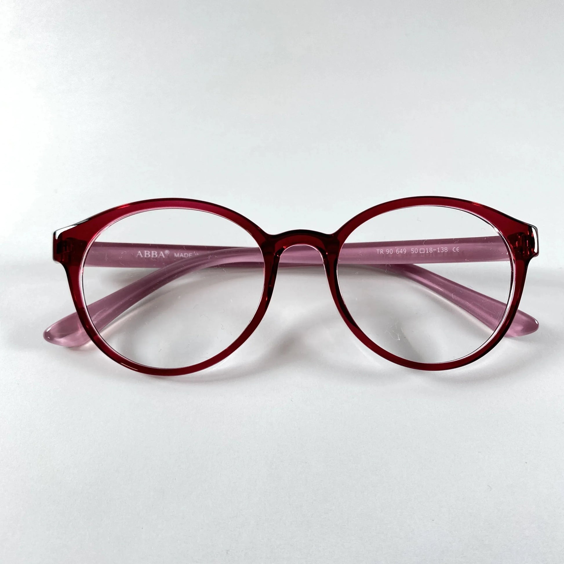 Round burgundy eyeglasses with clear lenses on a white background