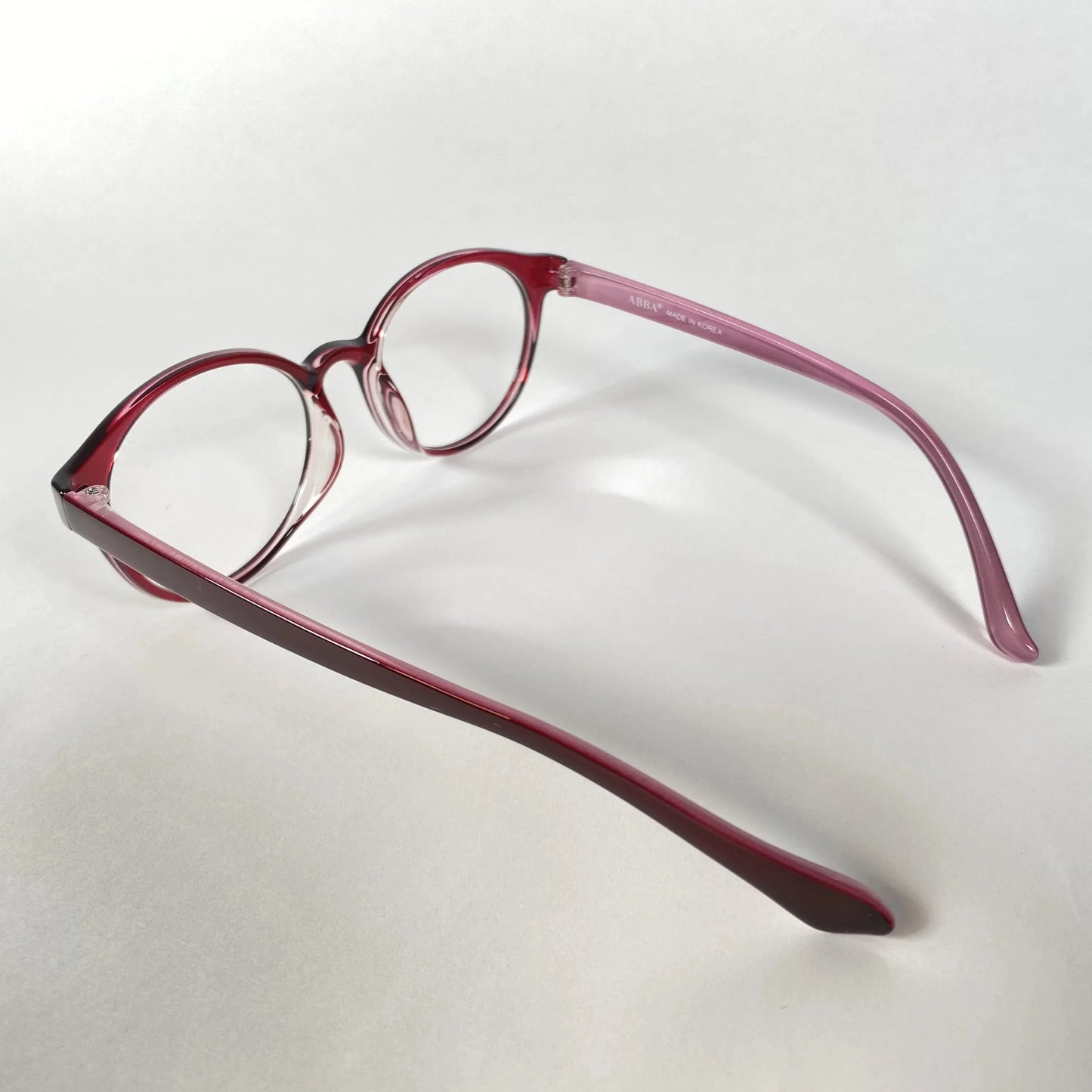 Round burgundy eyeglasses with clear lenses on a white background