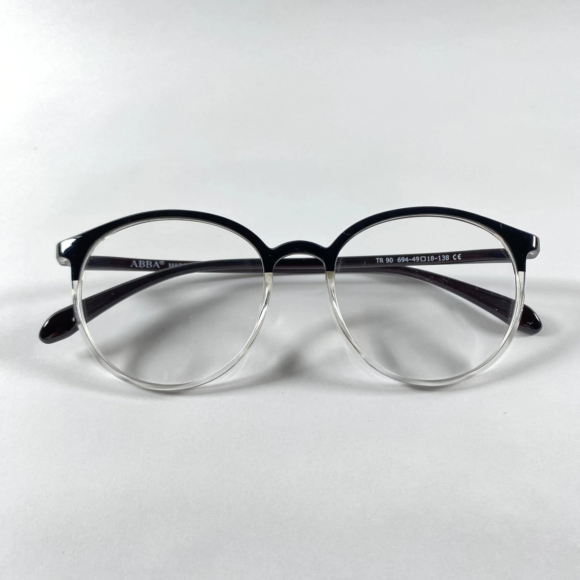 Round black clear plastic eyeglasses with transparent lower rims on white background
