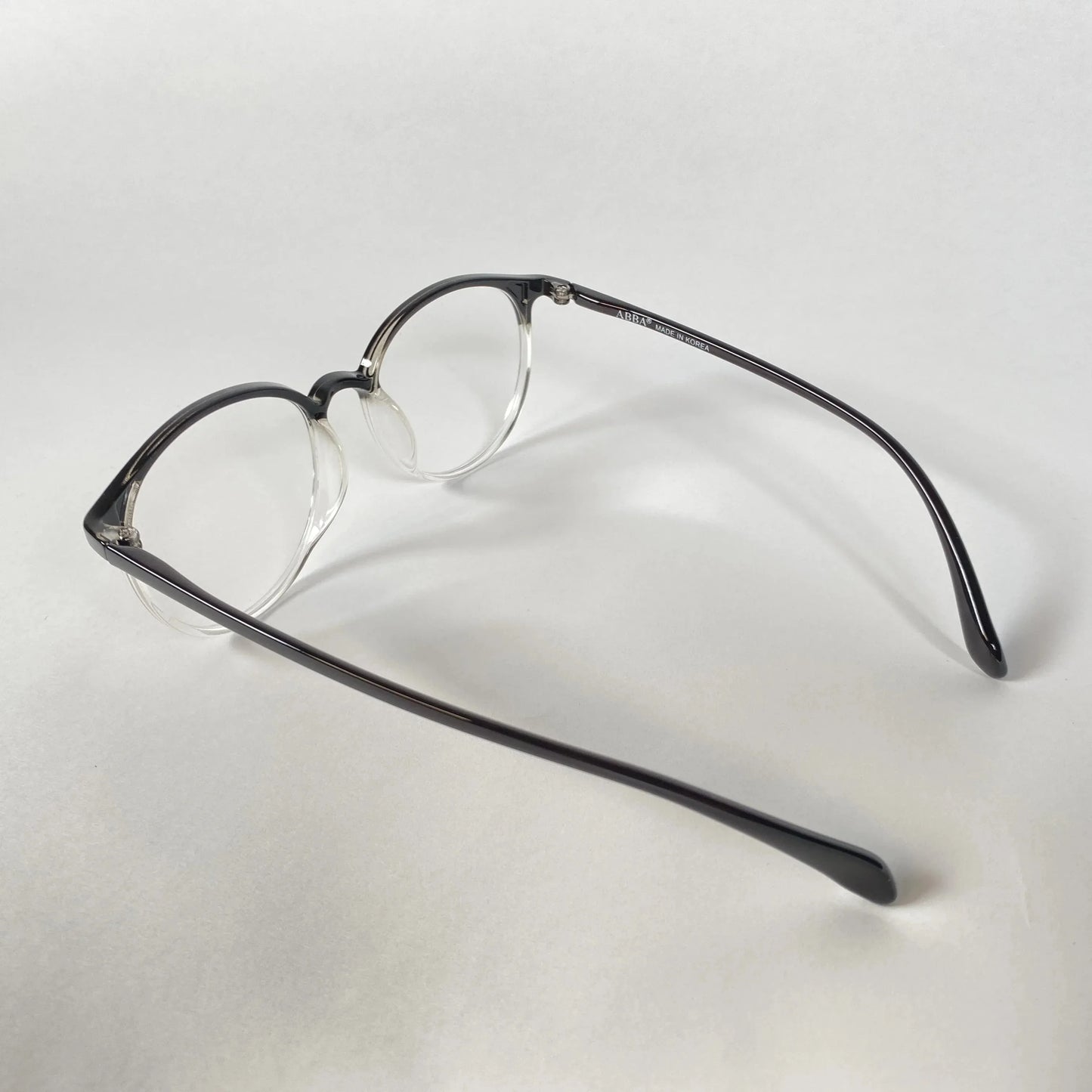 Black clear round eyeglasses with acetate frame on white background, side angle view