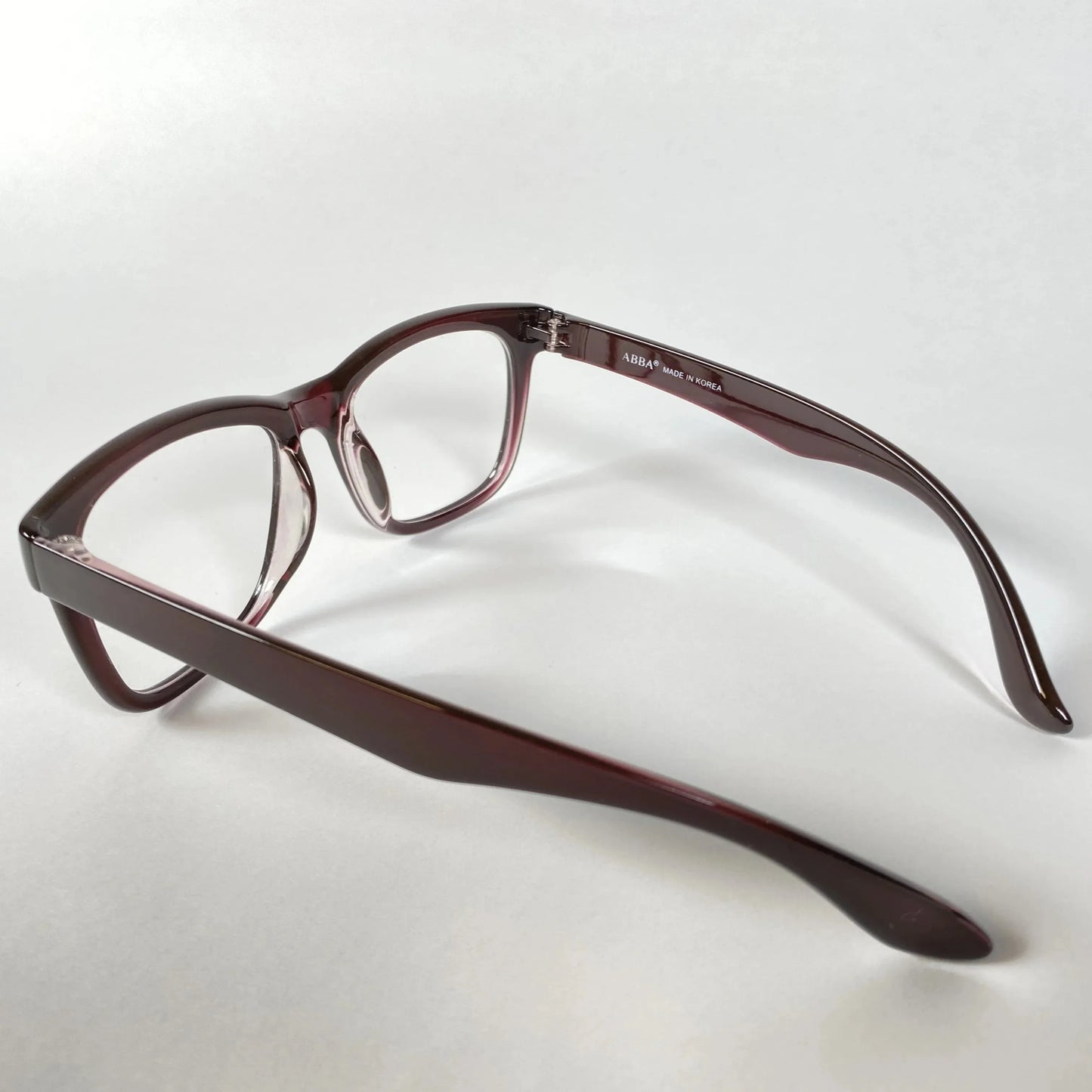 Side view of horn-rimmed eyeglasses with burgundy acetate frame on white background