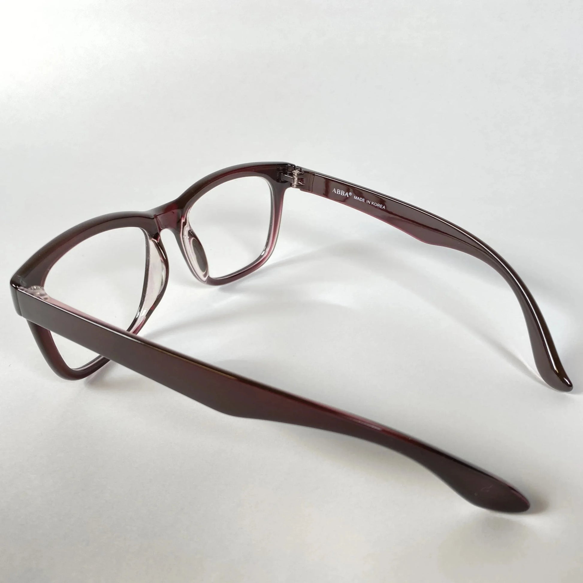 Side view of horn-rimmed eyeglasses with burgundy acetate frame on white background