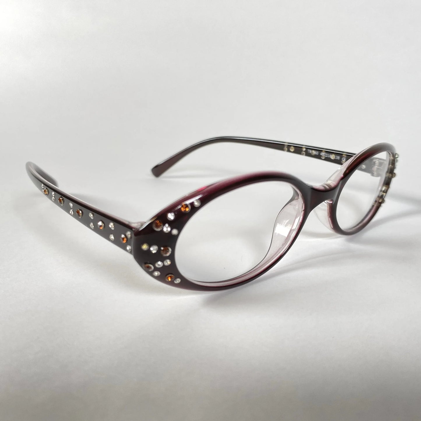 Burgundy oval eyeglasses with crystal rhinestone accents on frame and temples, white background