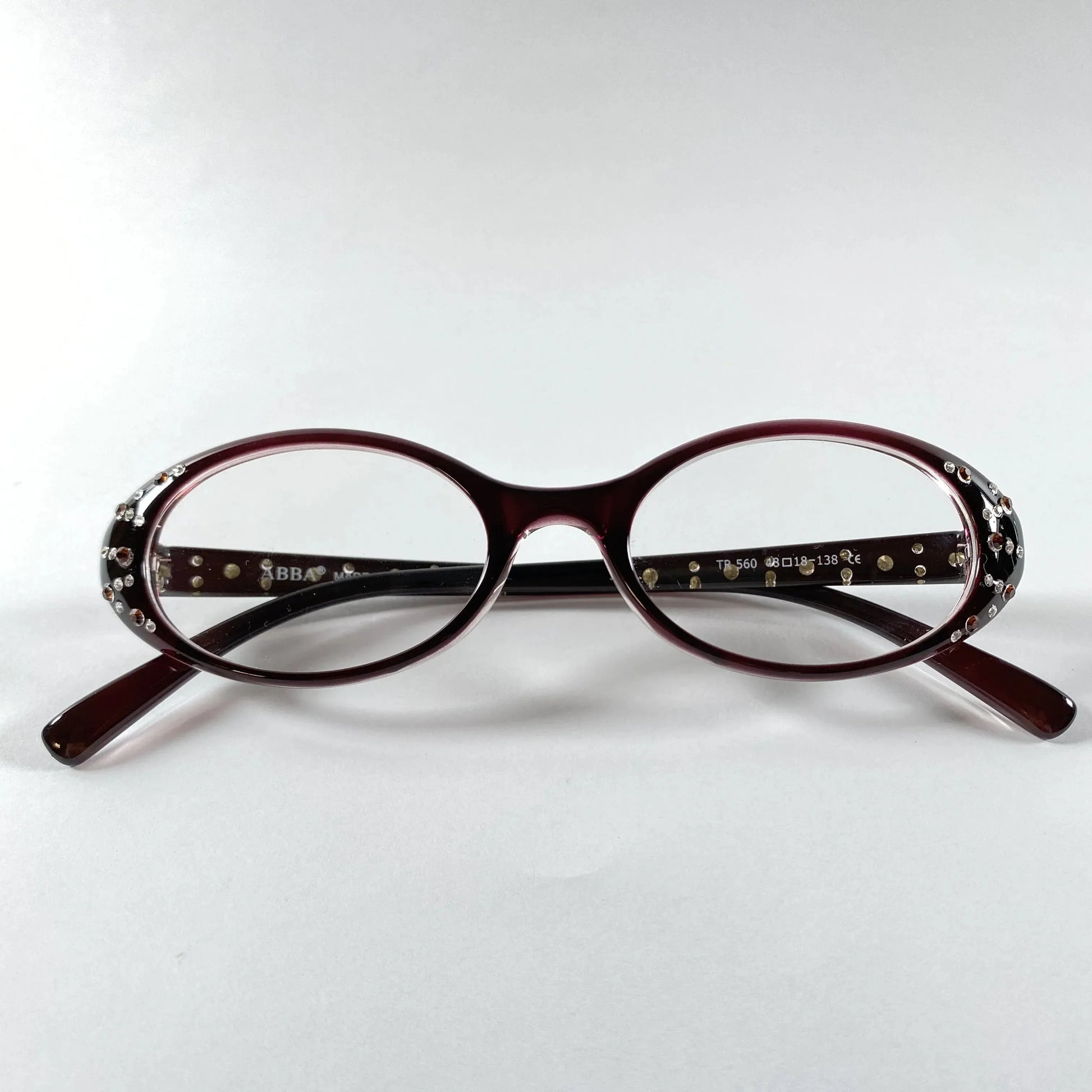Oval burgundy glasses with crystal embellishments on the temples, product on white background