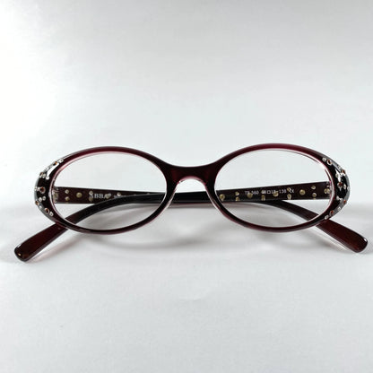 Oval burgundy glasses with crystal embellishments on the temples, product on white background