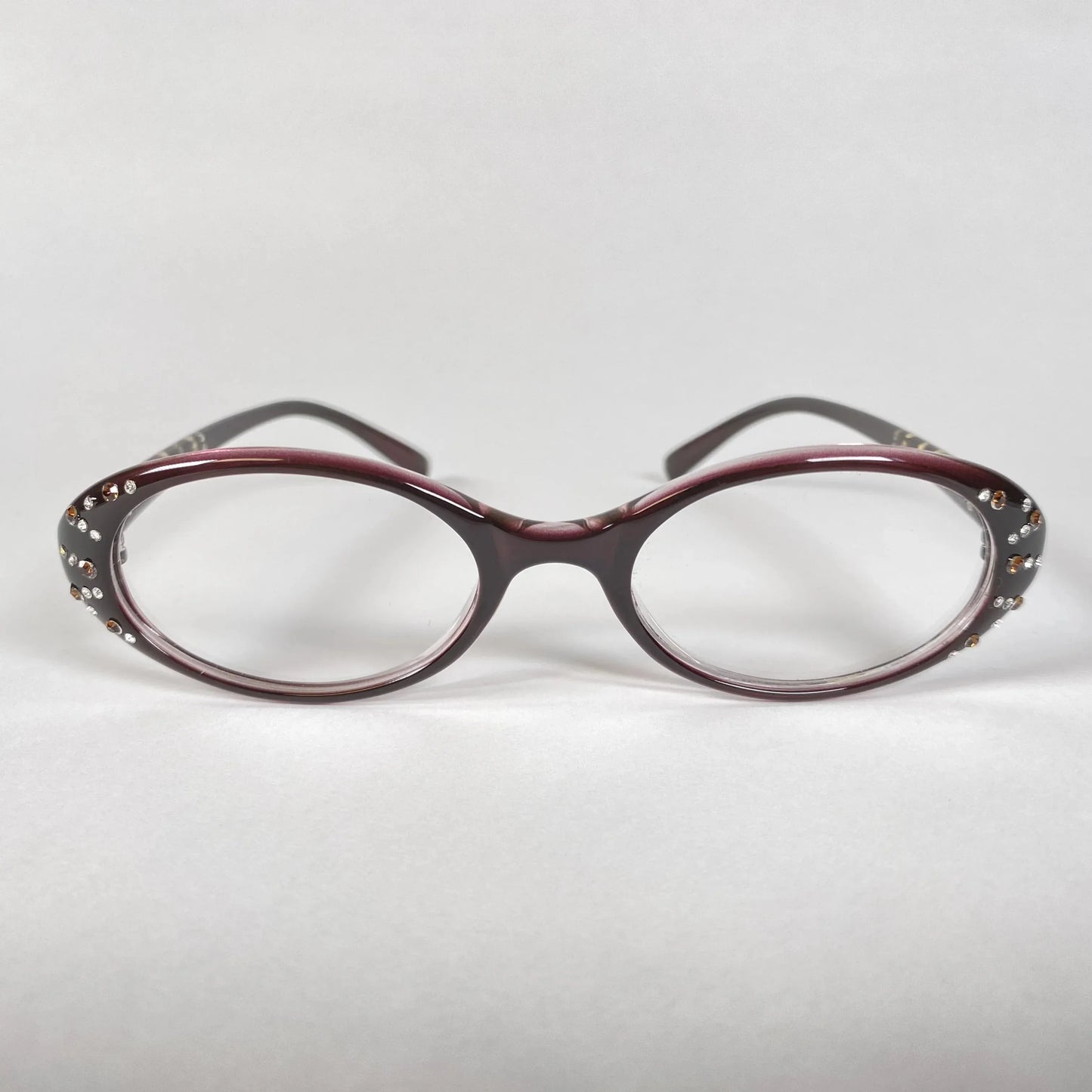 Oval burgundy eyeglasses with crystal accents on frame, stylish eyewear on white background
