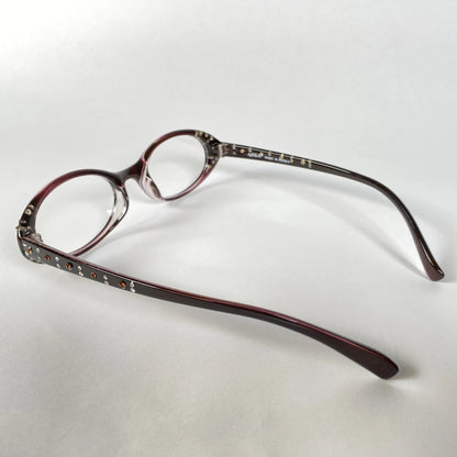 Round crystal-studded maroon eyeglasses with decorative temples on white background