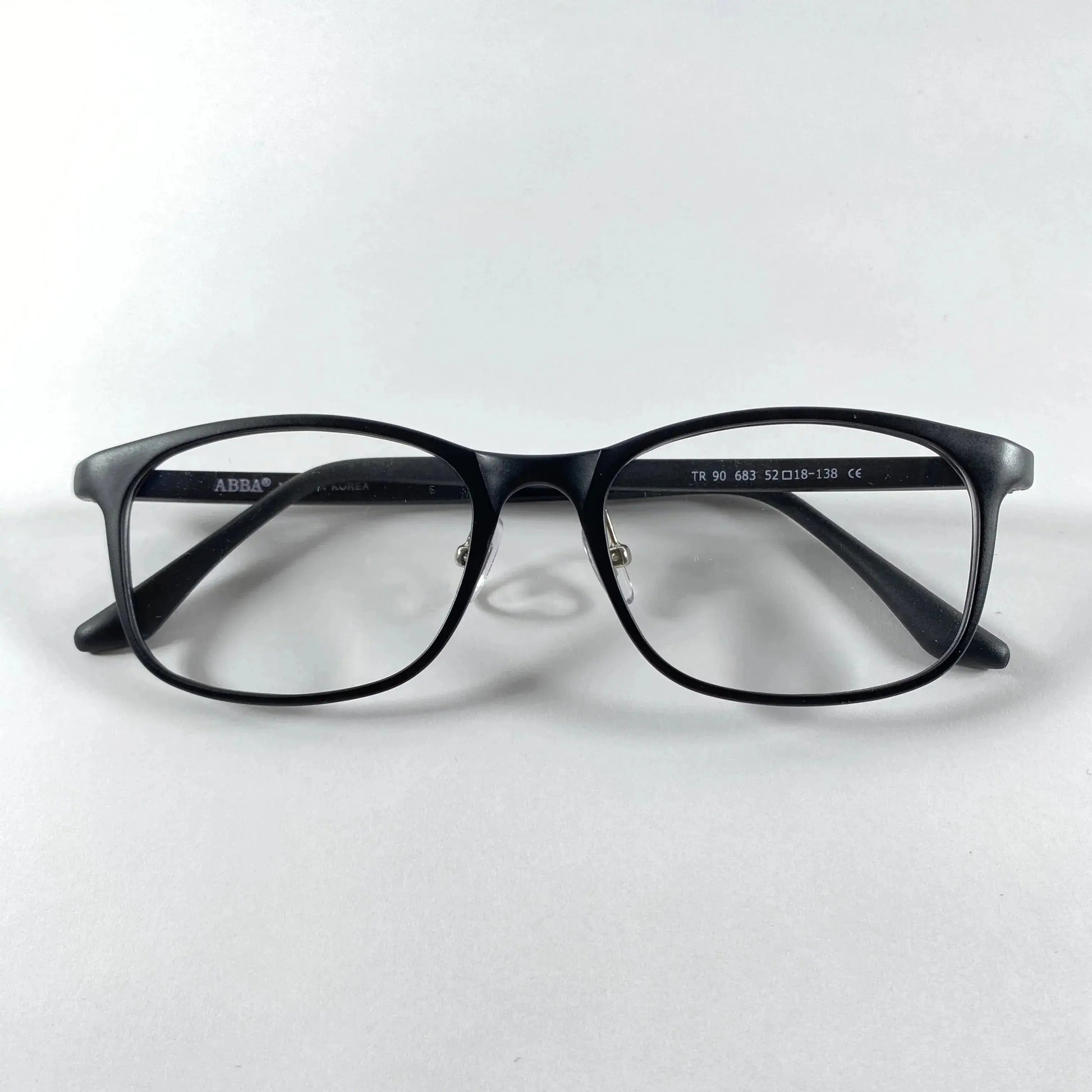 Black square eyeglasses with clear lenses on a white background, ABBA brand detail visible