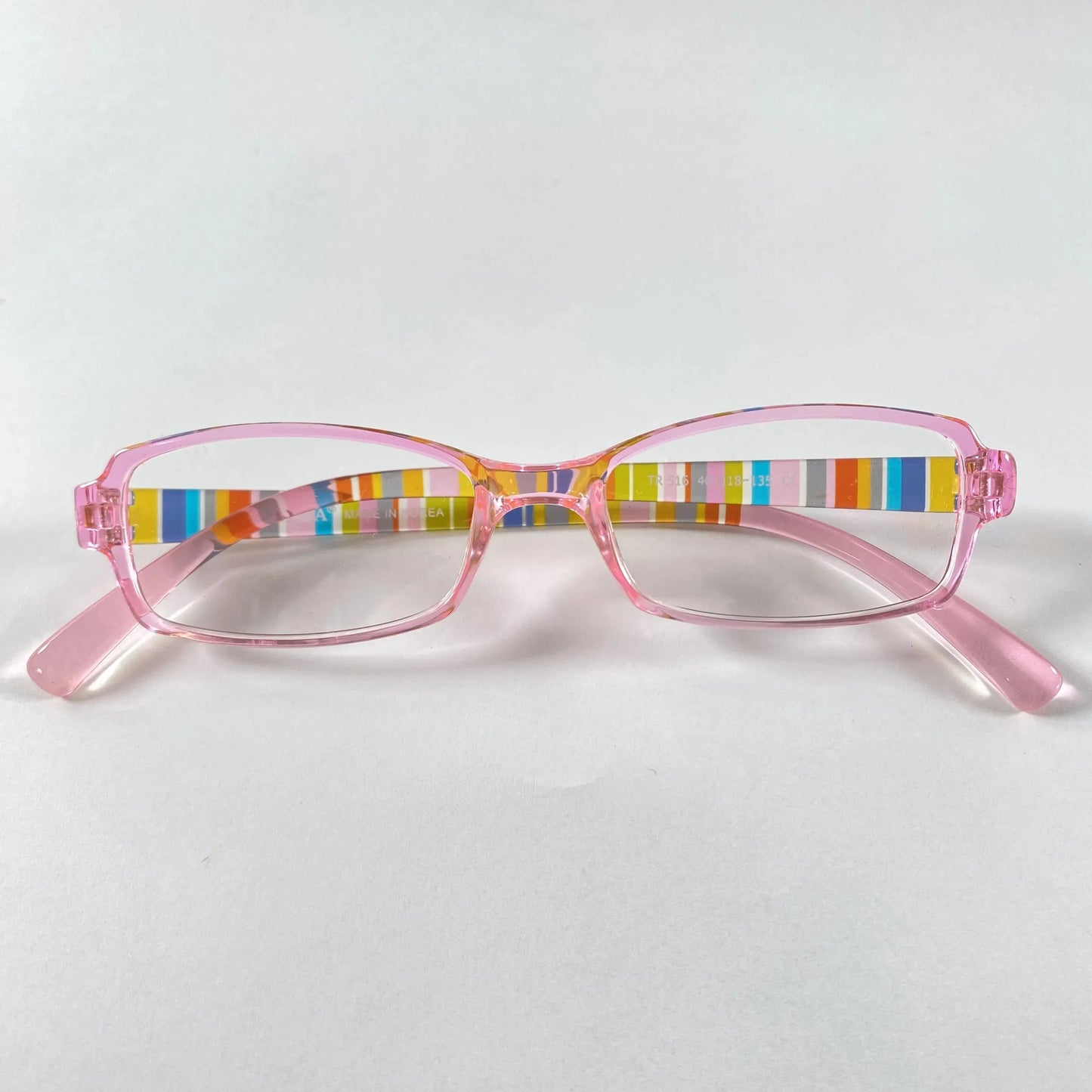 Pink kids eyeglasses with colorful striped arms on white background