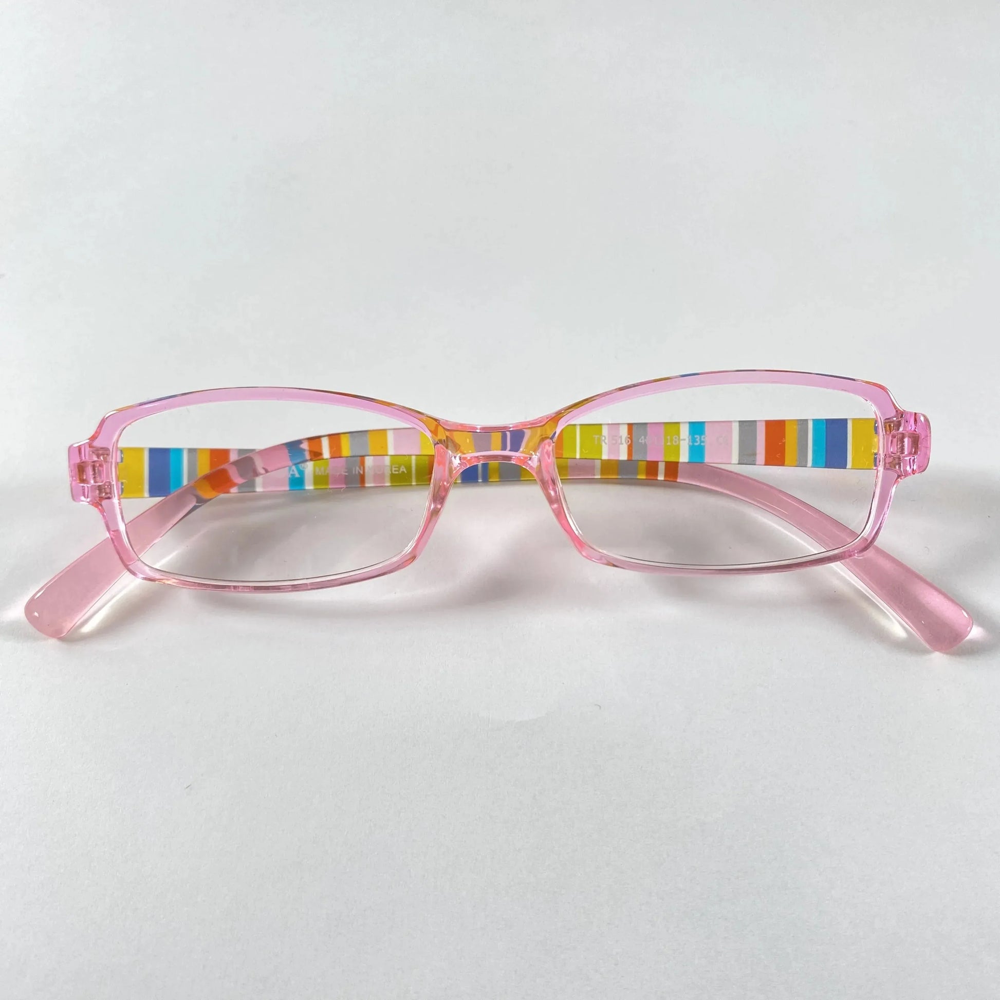 Pink kids eyeglasses with colorful striped arms on white background