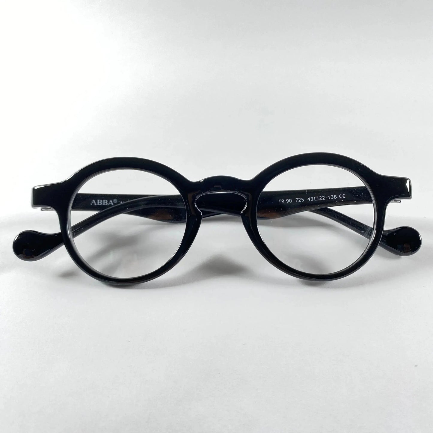 Black round eyeglasses with glossy frame and metal detail on white background