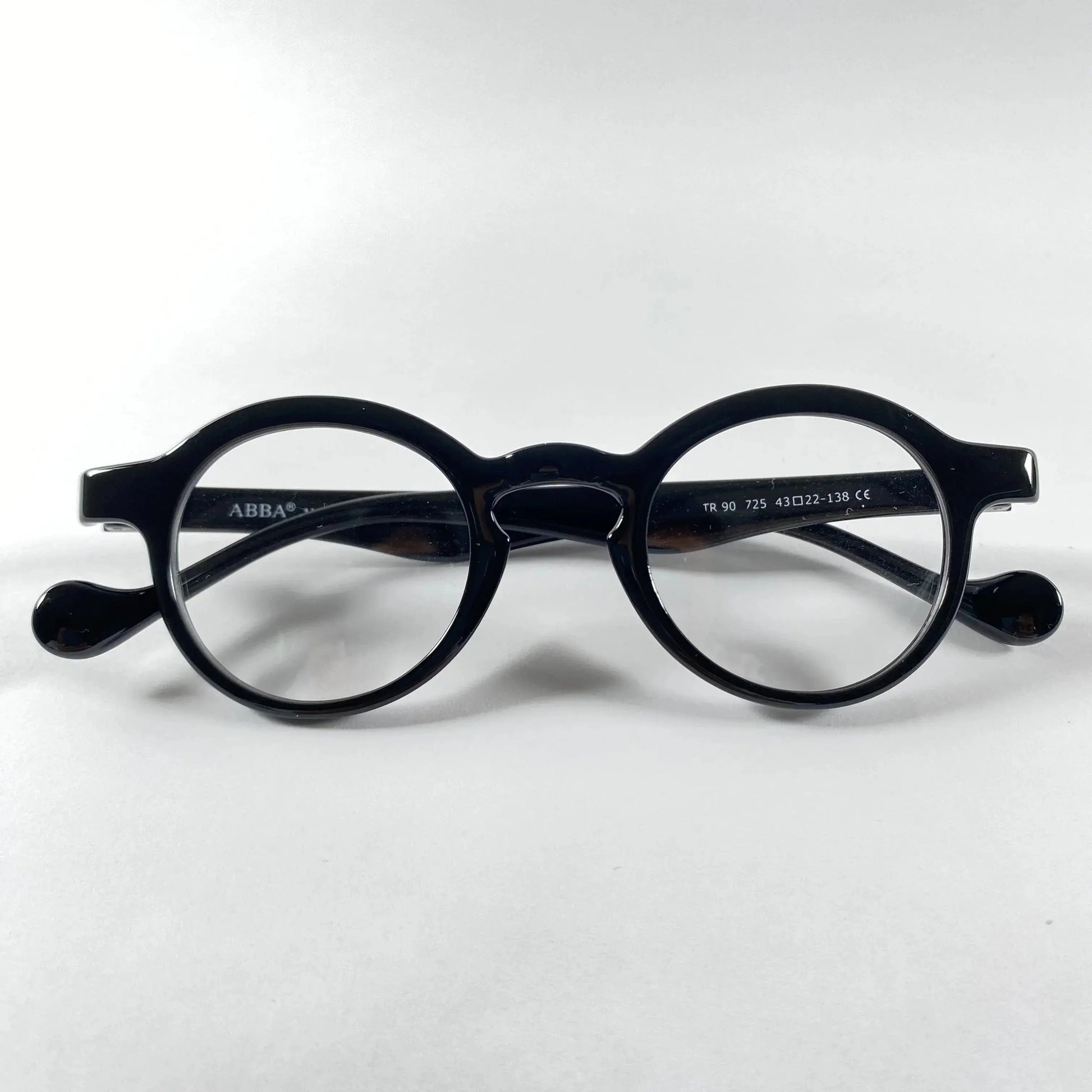 Black round eyeglasses with glossy frame and metal detail on white background