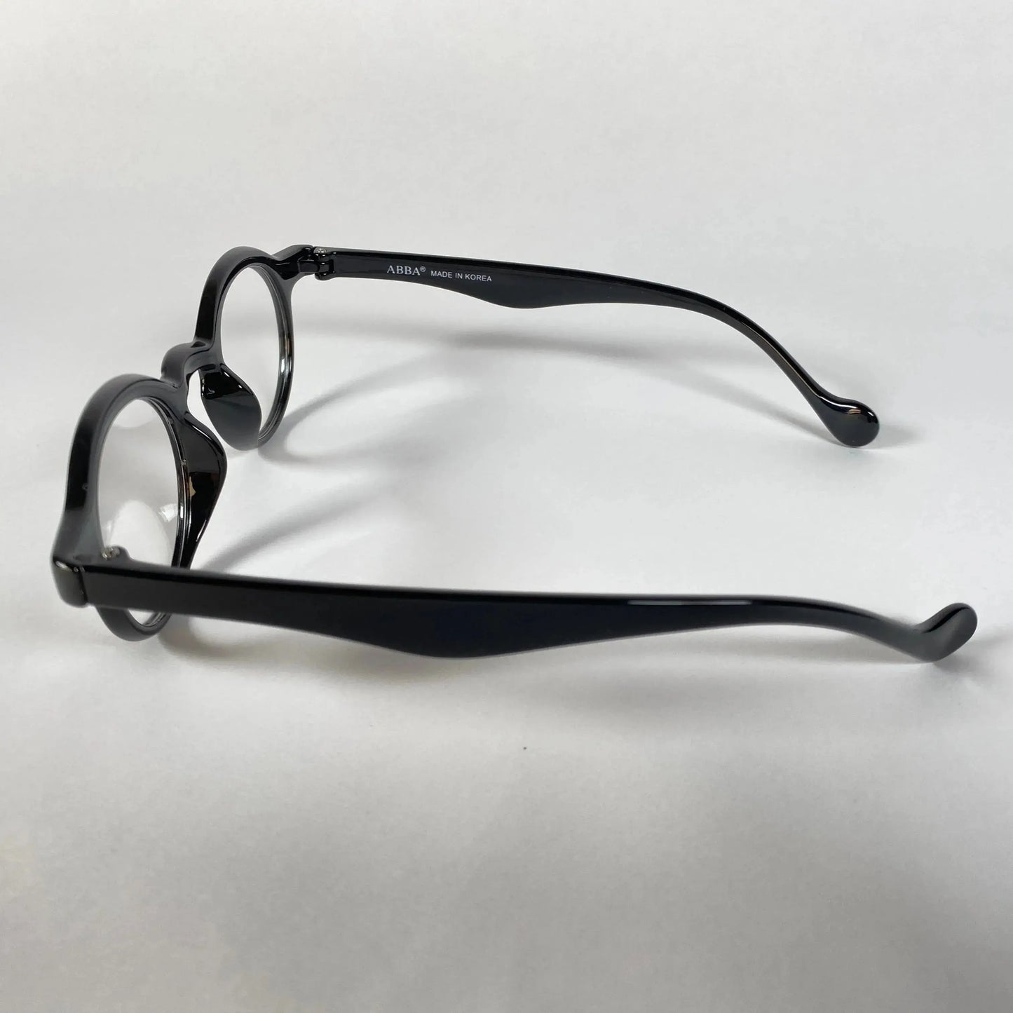 Black round metal eyeglasses with curved arms on white background