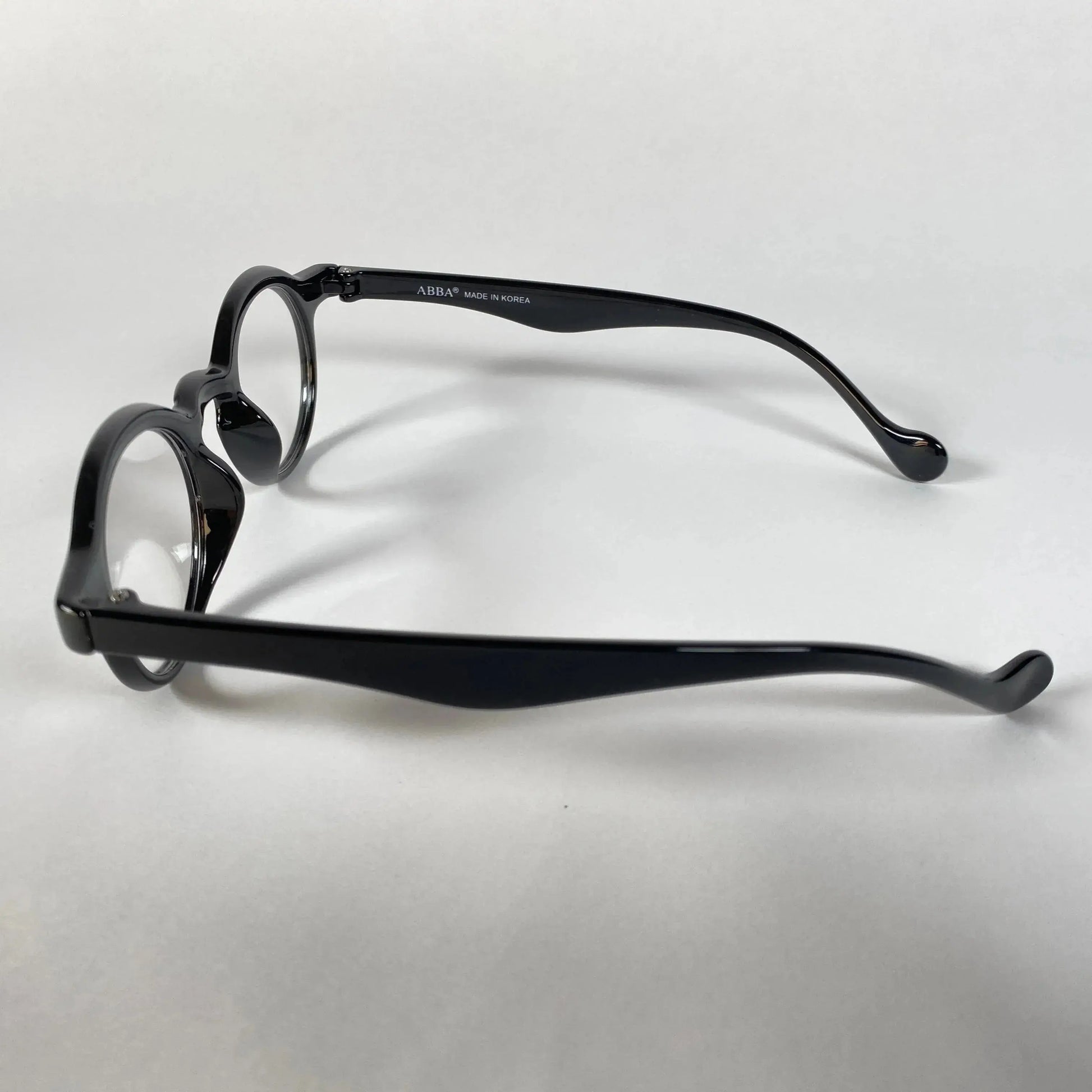 Black round metal eyeglasses with curved arms on white background