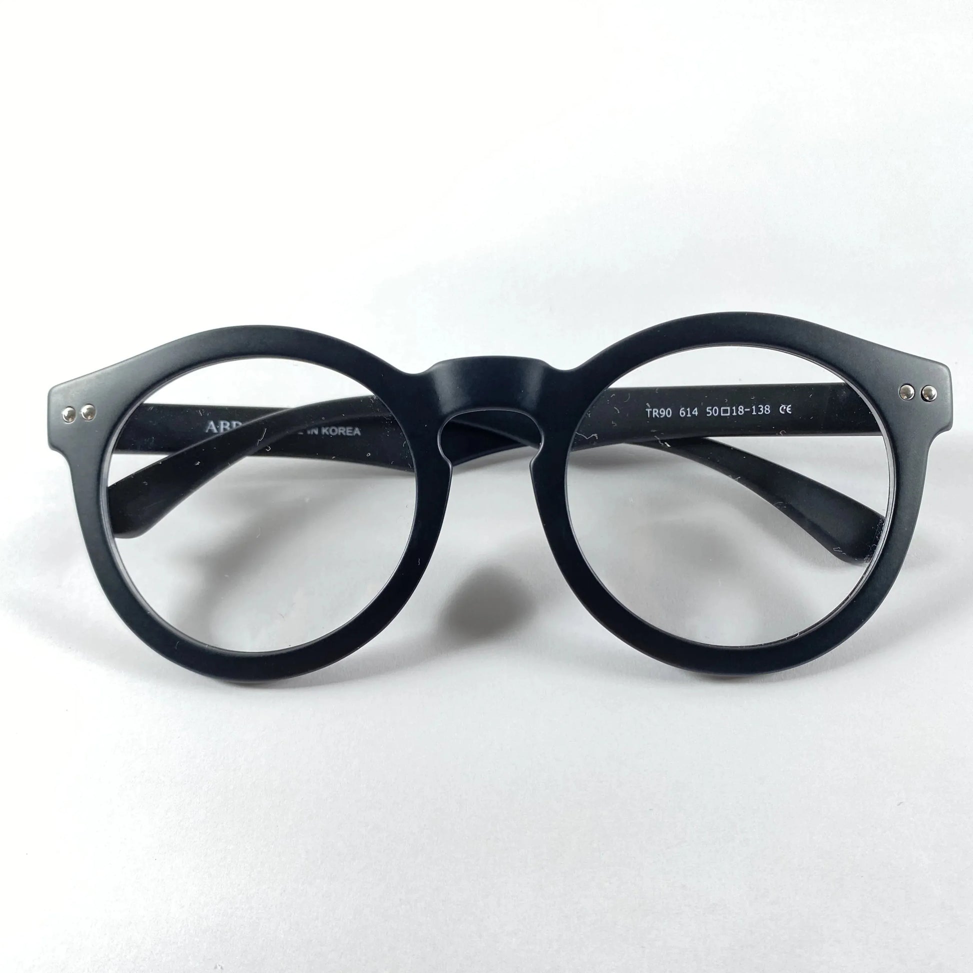 Black round eyeglasses frame with clear lenses on white background