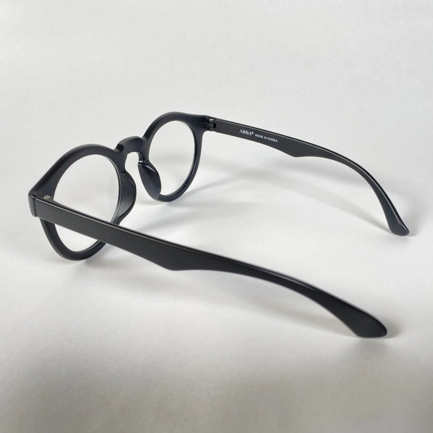 Black round eyeglasses with thick frames on white background, side view