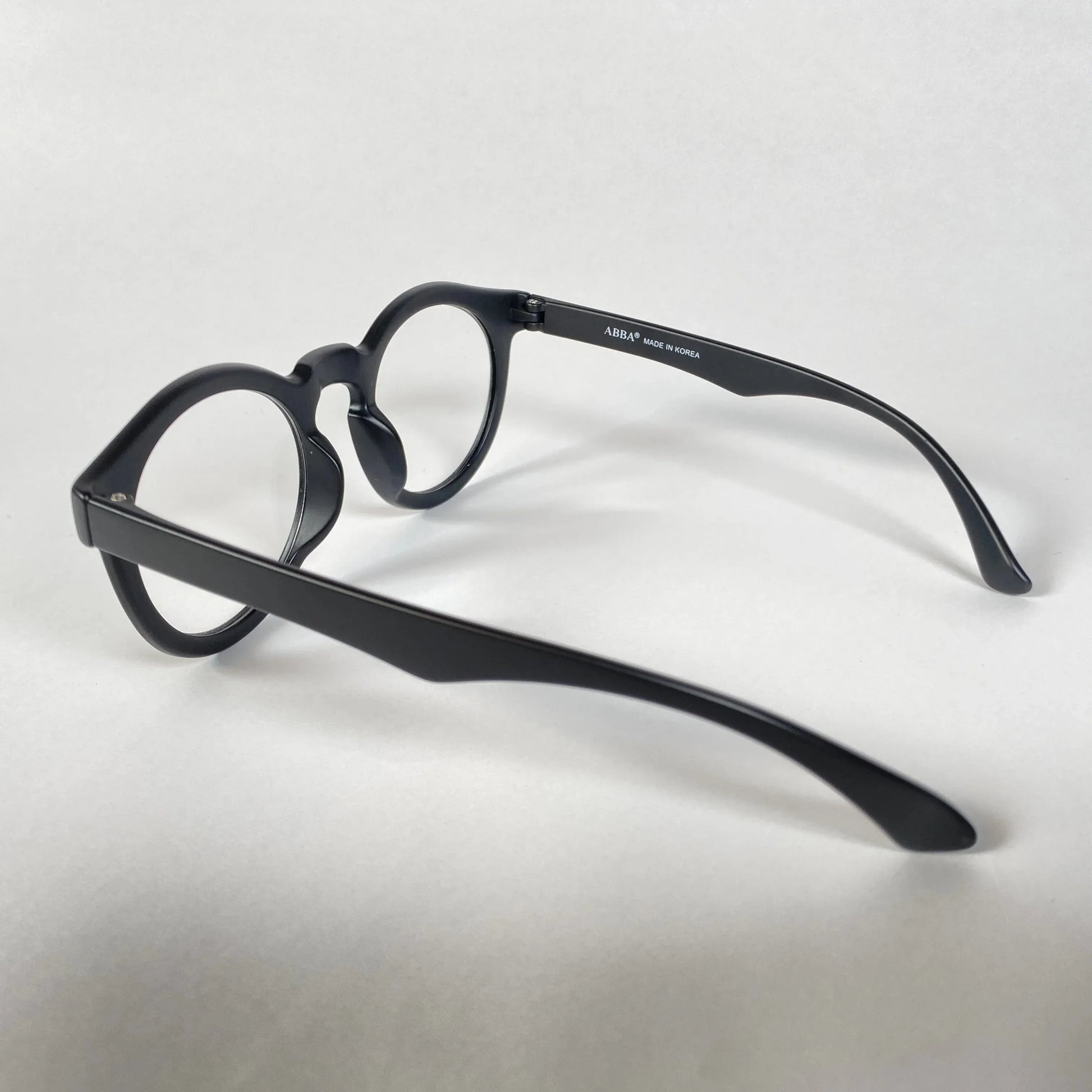 Black round eyeglasses with thick frames on white background, side view