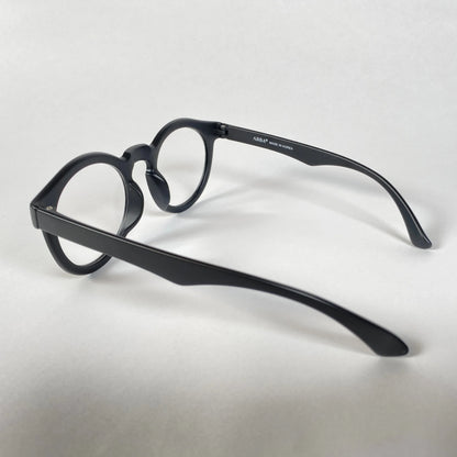 Black round eyeglasses with thick frames on white background, side view